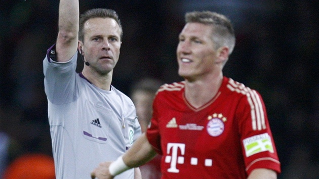 Bastian Schweinsteiger, záloník Bayernu Mnichov, inkasuje od rozhodího lutou