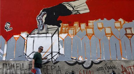 ek prochází v Aténách kolem oputné budovy s grafitti odkazujícím na