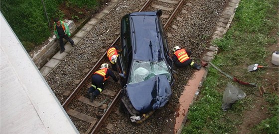 Hasii pipravují havarované auto k vyzvednutí z kolejit.