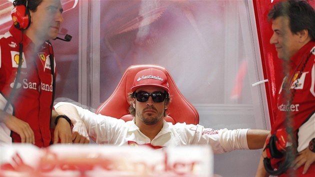EKÁNÍ. panlský jezdec Fernando Alonso sedí a vykává mezi leny svého týmu.