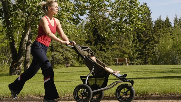 Matka s díttem v koárku na procházce v parku