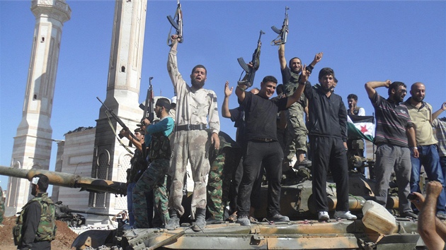 Bojovnci Syrsk osvobozeneck armdy se v provincii Aleppo raduj na znienm tanku Asadovch jednotek (20. ervence 2012)