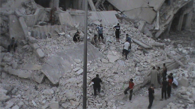 Zbr ukazuje obyvatele ped zdemolovanm domem v Homsu (11. srpna 2012)