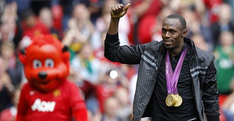 Usain Bolt v roce 2012 na Old Trafford ped zápasem Manchesteru United zdraví diváky a ukazuje zlaté medaile z londýnské olympiády.