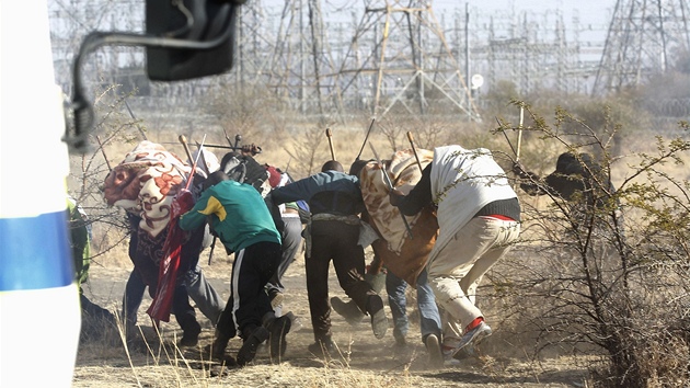 Stvkujc hornci z platinovho dolu firmy Lonmin v jihoafrickm mst Marikana utkaj ped policejn stelbou (16. srpna 2012)