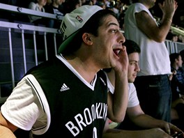 TO U MUSÍ BEJT KO. Tenhle divák v hale Brooklynu Nets telefonuje, pije pivo,