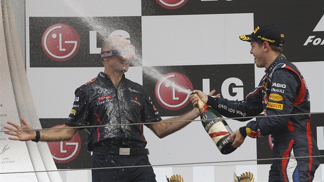 Sebastian Vettel coby ampion Velk ceny Koreje formule 1 sprchuje ampaskm Adriana Neweyho, prvnho mue stje Red Bull.