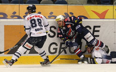 Hokejisté Liberce (v bílém) a Chomutova bojují u mantinelu o puk.