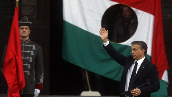 Viktor Orbán zdraví své píznivce ped symbolickou vlajkou maarské protikomunistické revoluce roku 1956