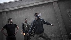 Syrský povstalec hází v Aleppu podomácku vyrobeným granátem po pozicích