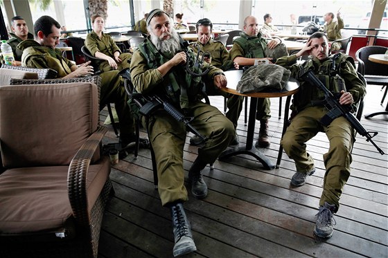 Izraeltí vojáci v kavárn sledují televizní zpravodajský poad vnovaný výbuchu náloe v autobusu v Tel Avivu.