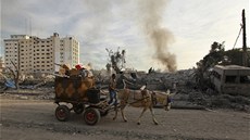 Palestinec se svým vozíkem projídí kolem trosek budov zniených pi izraelském