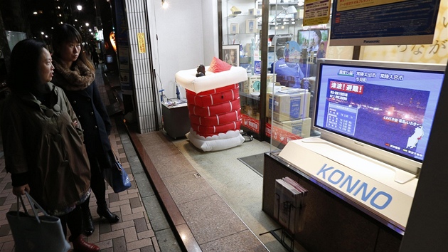 Kolemjdouc sleduj v ulicch Tokia zprvy o zemtesen (7. prosince 2012).