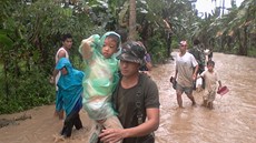 Vojáci pomáhají Filipíncm dostat se ze zaplavené oblasti. Na zemi udeil