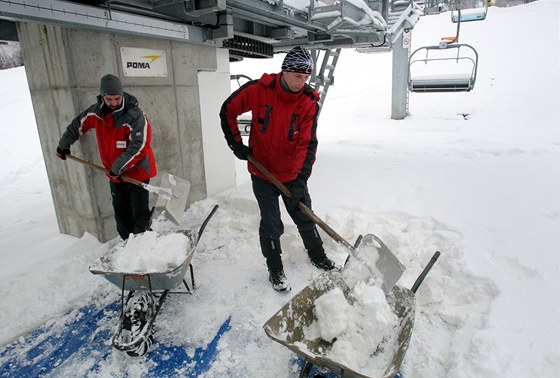 Milo Doleal (vlevo) a Jií Novák odklízejí navátý sníh z nástupního prostoru