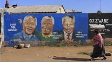 Jihoafrianka kráí kolem zdi s portrétem Nelsona Mandely na johannesburském