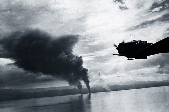 Bombardér Douglas SBD Dauntless amerického námonictva letí nedaleko hoících