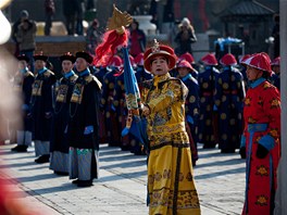 ínský herec pevleený za vládce dynastie ching ukazuje pihlíejícím bhem...