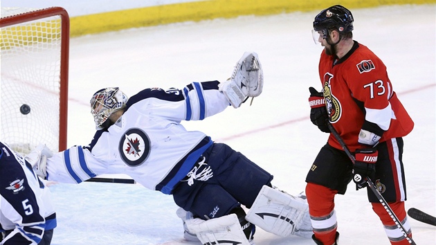 Brank Winnipegu Ondej Pavelec se marn natahuje po stele hokejist Ottawy. 