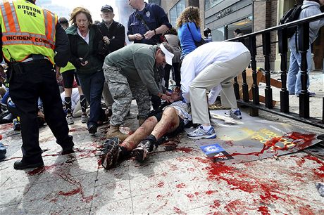 Lidé pomáhají jednomu ze zranných bc maratonu v Bostonu. (15. dubna 2013)