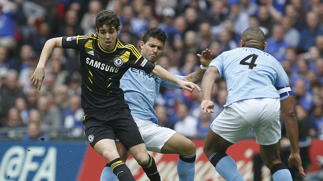 Drobn mladek Oscar z Chelsea se pokou o slalom mezi robustnjmi hri Manchesteru City. Vpravo je Vincent Company, vlevo Sergio Aguero. 
