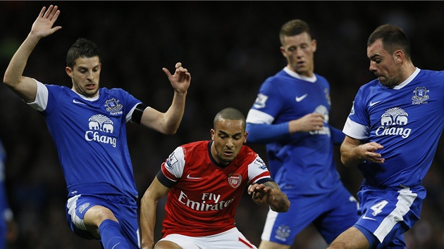 Theo Walcott (v ervenm dresu) z Arsenalu se probj obranou Evertonu.