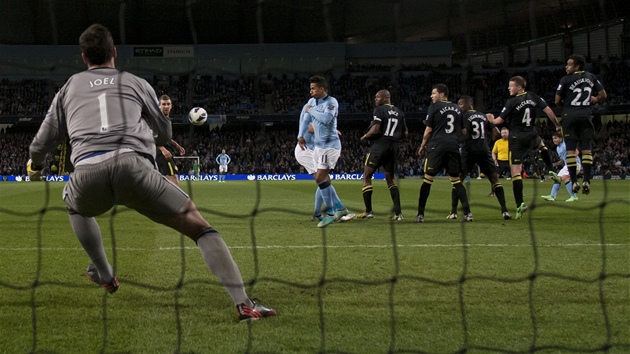 Carlos Tvez (druh zprava) z Manchesteru City pekonv ze Wiganu i jeho glmana Joela Roblese.