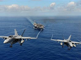 Pár Super Hornet  F/A-18E s vytaenými podvozky po prletu nad mateskou lodí....