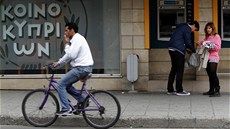Kypřan projíždí kolem největší místní banky Bank of Cyprus v Nikósii. Kypřan projíždí kolem největší místní banky Bank of Cyprus v Nikósii.
