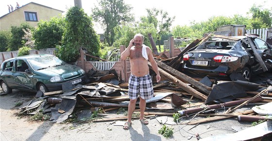 Josef Kobza u trosek stechy ze svého domu. Trámy zavalily i jeho auto (vlevo)...