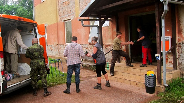 Pracovnci lovka v tsni distribuuj vci potebn na odklzen kod po povodni v Rudnku.