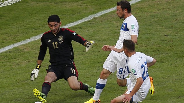 Mexick brank Guillermo Ochoa zasahuje ped italskm duem Claudio Marchisio (uprosted) a Emanuele Giaccherini. 