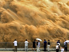 VELKÝ ÚKLID. Lidé pozorují pinavou vodu tryskající z vodní nádre Siao-lang-ti...