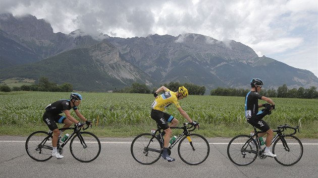 MEZI SVMI. Ldr Chris Froome ve lutm dresu, kolem nj parci z tmu Sky. Nejhor v 17. etap Tour de France jet pijde. 