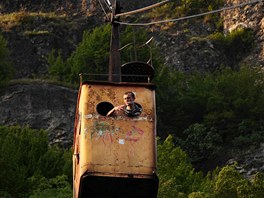 03 A miner smokes a cigarette through the cabin portholes of "Peace" tramway...