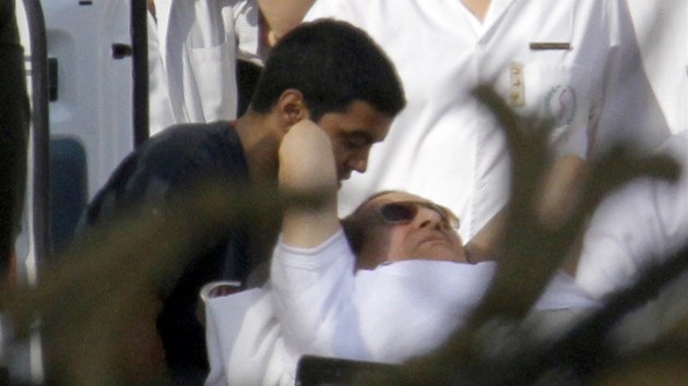 Egyptsk policie a zdravotnci eskortuj Husnho Mubaraka z helikoptry do sanitky pot, co ho vrtulnk pevezl z vazby do vojensk nemocnice (22. srpna 2013)