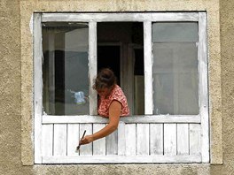 A woman paints the window of her apartment in Aninoasa, 330 km (202 miles) west...