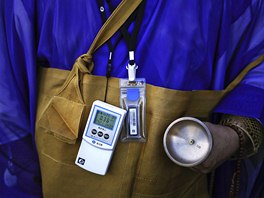 A Buddhist monk wears a Geiger counter as he leads a small funeral ceremony for...