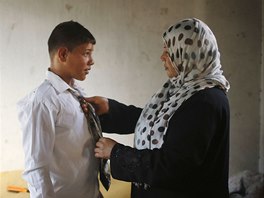 The mother of young Palestinian groom Ahmed Soboh, 15, helps him prepare for...