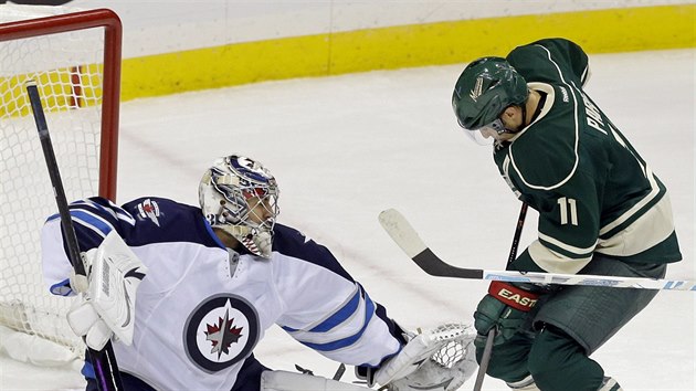 Glman Ondej Pavelec z Winnipegu zasahuje v duelu s Minnesotou, stn mu Zach Parise.