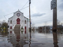 Kostel stojící na zaplavené ulici a stejný kostel ve tvrti New Dorp Beach.
