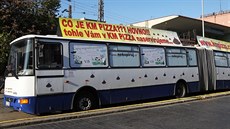 Kloubový autobus s vulgárními nápisy a figurou obence (leí za bannerem),...