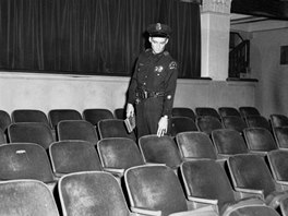 Policista ukazuje na sedadlo v dallaském Texaském divadle kde sedl Lee Harvey...