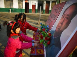 Students put plastic flowers next to a portrait of China's late chairman Mao...