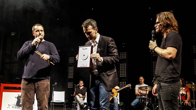 Kapela Krytof dostv na koncert v Ostrav pamtn plaketu od vherce charitativn aukce, kterou odstartovala sbrka muzikant pro dti nemocn rakovinou. Bohdan koda (vlevo) drabu vyhrl o jedinou korunu. (13. prosince 2013)