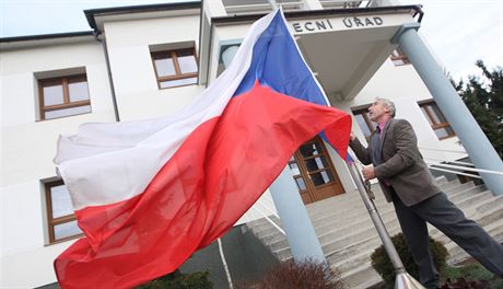 Starosta lutavy Stanislav Kolá vyvuje vlajku ped obecním úadem, kde lidi...