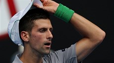UNAVENÝ FAVORIT. Novak Djokovič si s unaveným výrazem upravuje kšiltovku v... UNAVENÝ FAVORIT. Novak Djokovič si s unaveným výrazem upravuje kšiltovku v...