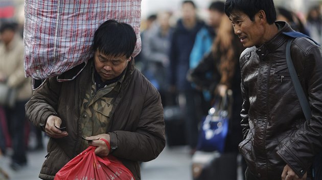 Mu s tkm nkladem na rameni si kontroluje jzdenku na vlak ped Hlavnm ndram v Pekingu. Cestuje za rodinou na oslavy Novho roku.