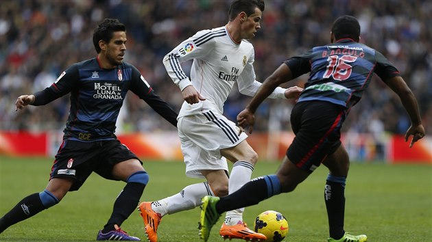 MEZI DVMA. Hvzda Realu Madrid Gareth Bale (uprosted) se proplt mezi dvma protihri z Granady - zastavit se ho sna Brayan Angulo (vpravo) i Jose Luis Garcia "Recio".