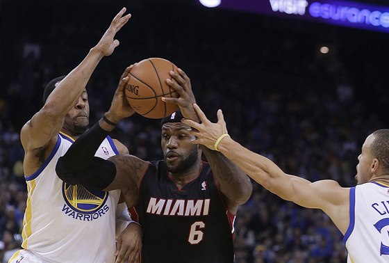 LeBron James z Miami si razí cestu mezi hrái Golden State Warriors. Vlevo je
